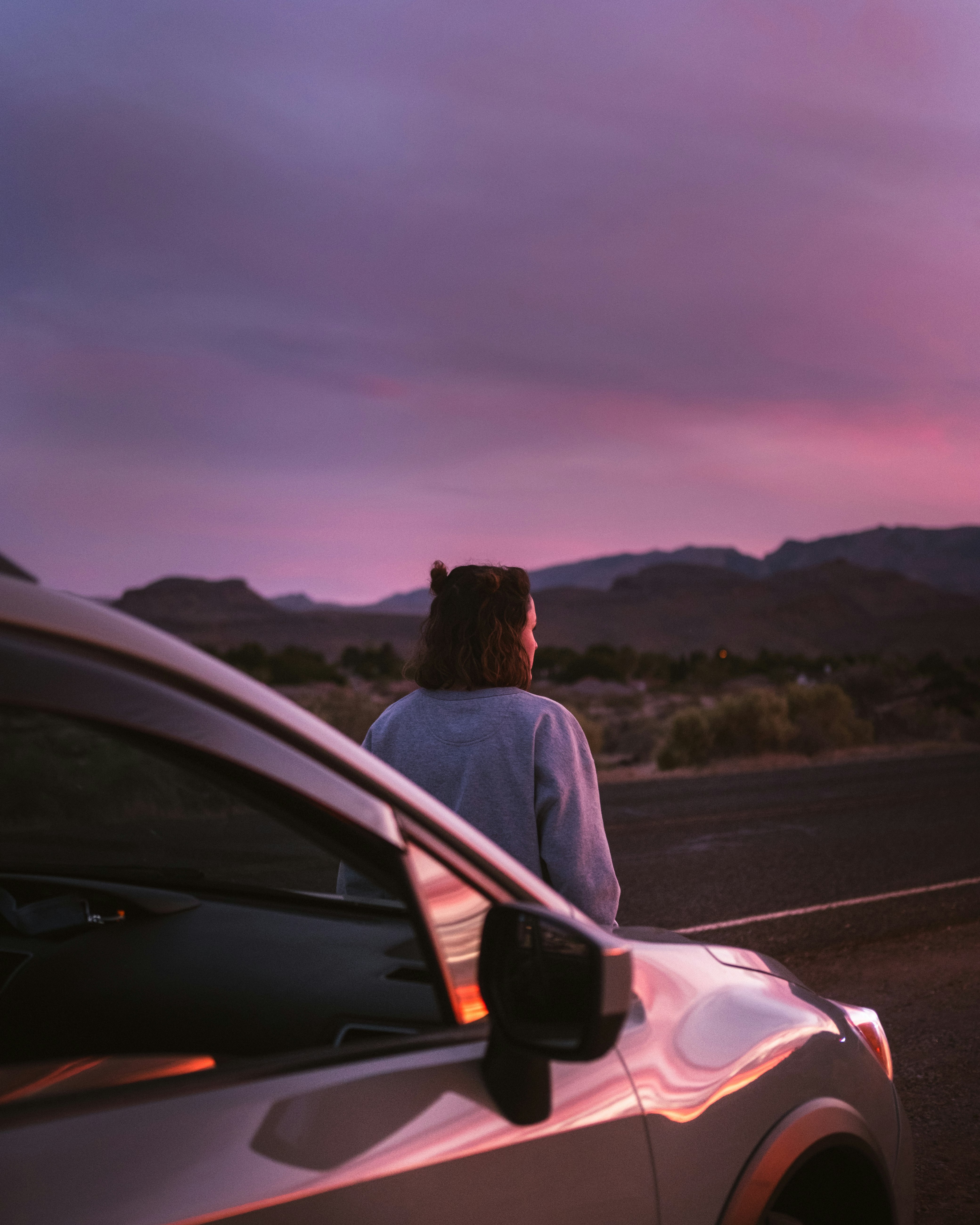 man in white shirt sitting on car hood during daytime